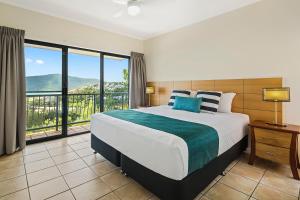 a bedroom with a large bed with a large window at Sea Star Apartments in Airlie Beach