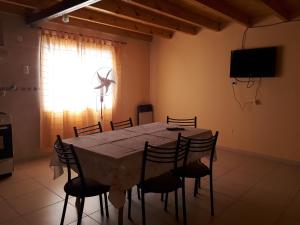 a dining room with a table with chairs and a television at Departamentos San Expedito in Malargüe