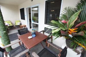 Coral Sands Apartments في راروتونغا: طاولة وكراسي خشبية على شرفة تحتوي على نباتات