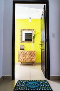 Habitación con pared amarilla y puerta con espejo. en Sun n' Sand Retreat, en La Chumicosa