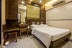 a bedroom with two beds and a desk and a mirror at City Guest House - Dadar in Mumbai