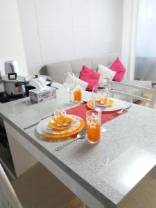 una mesa con dos platos y vasos de zumo de naranja en Highvill AST en Astaná