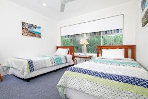 two beds in a room with a window at 26 Witta Circle, Noosa Heads in Noosa Heads