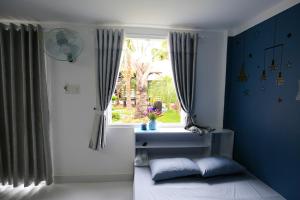 ein Schlafzimmer mit blauen Wänden und einem Fenster in der Unterkunft Zan HomeStay in Buon Ma Thuot
