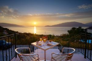 a table and chairs on a balcony with the sunset at Fotini in Ayia Evfimia
