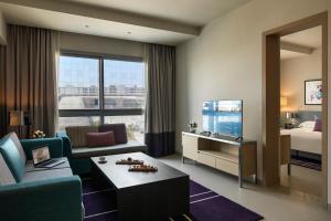 a hotel room with a bed and a living room at Capital Centre Arjaan by Rotana in Abu Dhabi