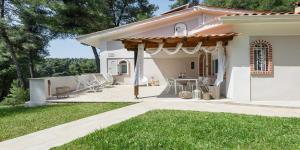 a white house with a pergola on a patio at Ekatis Houses in Sani in Sani Beach