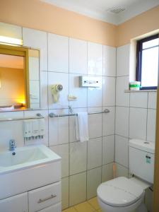 a white bathroom with a toilet and a sink at Bella Vista Motel in Gosford