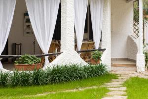 a house with white curtains and plants in a yard at La Villetta in Pula