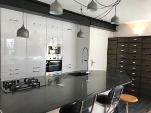 a kitchen with a black counter with chairs and appliances at La chouette au bouleau in Hargnies