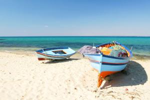 two boats sitting on a beach near the ocean at immeuble selma 3 in Hammamet