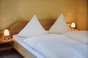 ein Bett mit weißer Bettwäsche und Kissen darauf in der Unterkunft Weingut Weich in Riol