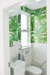 uma casa de banho com um WC branco e papel de parede tropical em 55 Zimbali wedge Ballito em Ballito