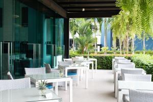 an outdoor patio with white tables and chairs at BlueSotel Krabi AoNang Beach- SHA Extra Plus in Ao Nang Beach