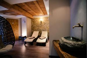 een badkamer met een wastafel en een bad met witte stoelen bij Hotel Pension Sonnegg in Saltusio