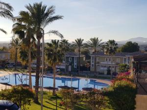 a view of a pool with palm trees and houses at Chalet Bonalba Golf in Alicante