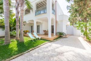 une maison blanche avec des palmiers et deux chaises dans l'établissement Villa Ferreri, à Specchiolla