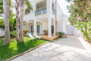a white house with palm trees and two chairs at Villa Ferreri in Specchiolla 