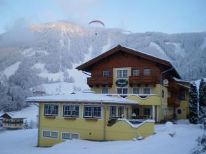 a building in the snow with a mountain in the background at Gasthof-Pension Strassreith in Werfenweng