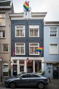 une voiture garée devant un bâtiment arborant un drapeau arc-en-ciel dans l'établissement Amistad hotel, à Amsterdam
