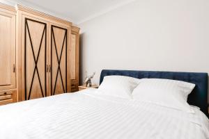 1 dormitorio con cama blanca y armario de madera en Apartament Indygo en Łomża