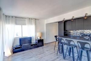 シッチェスにあるChic Sea View Apartment by Hello Homes Sitgesのキッチン(スツール付きのバー、テレビ付)