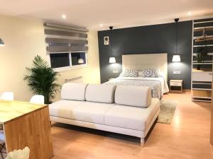 a bedroom with a white bed and a white couch at LOFT A 20' DE BARCELONA Y 7' DE LA UAB. in Barbera del Valles