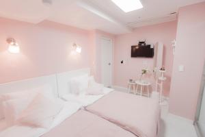 a white room with a bed and a tv on the wall at MJ Stay 2 in Seoul