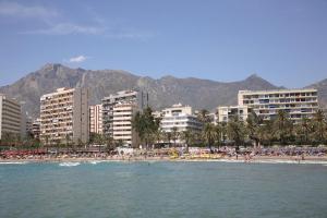 a beach with a bunch of people and buildings at Playa Fontanilla Apartments in Marbella