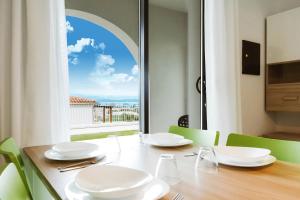 a dining room table with a view of a window at Geovillage Green Residence in Olbia