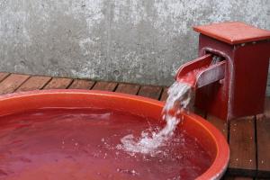a bucket of red water pouring into a red bird bath at Kuranoyado Matsuya in Fujikawaguchiko