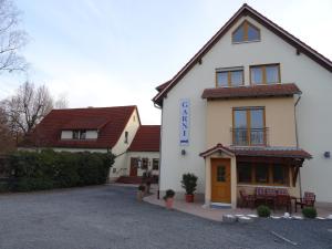 un grand bâtiment blanc avec une porte jaune dans l'établissement Restaurant - Garni bei Peppo, à Ebern