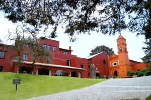 um edifício vermelho com uma torre de relógio e uma igreja em Hotel Hacienda San Martin em Toluca