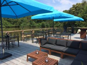 a deck with tables and chairs and blue umbrellas at Glamping Resort Bousset in Chiddes