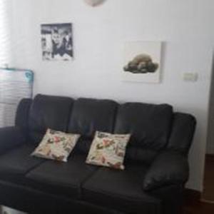 Sofá negro en la sala de estar con 2 almohadas en Apartments Svjetlana, en Trogir