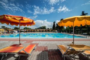 una grande piscina con sedie e ombrelloni di Campeggio Gasparina a Castelnuovo del Garda