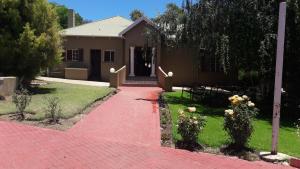 a house with a brick walkway in front of a yard at Beverly Corner Lodge in Matatiele