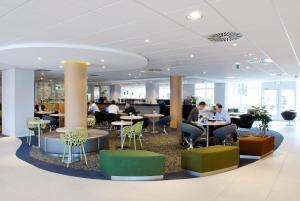 a lobby with tables and people sitting at tables at Novotel Eindhoven in Eindhoven