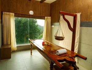 Zimmer mit einem Holztisch und einem Fenster in der Unterkunft Forest Canopy Thekkady in Thekkady