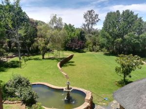 a garden with a fountain in the middle of a field at Moon and Sixpence Garden Guest House in Muldersdrift