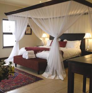 a bedroom with a canopy bed with white curtains at Moon and Sixpence Garden Guest House in Muldersdrift