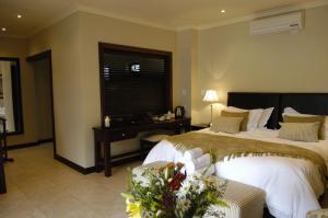 a bedroom with two beds and a table and a window at Moon and Sixpence Garden Guest House in Muldersdrift
