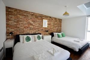a bedroom with two beds and a brick wall at N5 Townhouse, Brighton Sleeps 20 in Brighton & Hove