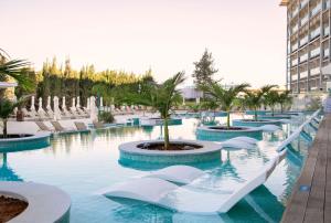 a pool at a resort with chairs and a palm tree at Asterias Beach Hotel in Ayia Napa