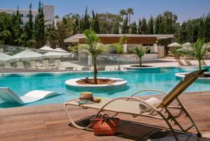 a resort pool with a chair and a palm tree at Asterias Beach Hotel in Ayia Napa