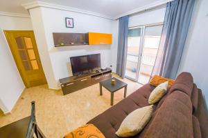 ein Wohnzimmer mit einem Sofa und einem Flachbild-TV in der Unterkunft Homely Apartments Noruega in Torrevieja