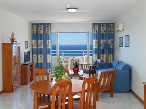Apartamentos Jardins da Rocha في بورتيماو: غرفة معيشة مع طاولة وأريكة زرقاء