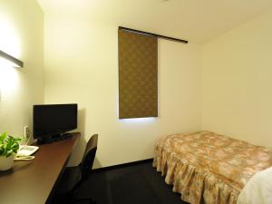 ein Hotelzimmer mit einem Bett und einem Schreibtisch mit einem Computer in der Unterkunft Business Hotel Prince in Takamatsu