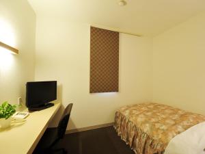 ein Hotelzimmer mit einem Bett und einem Schreibtisch mit einem Computer in der Unterkunft Business Hotel Prince in Takamatsu
