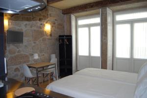 1 dormitorio con cama, mesa y TV en Casa Dos Caldeireiros, en Oporto